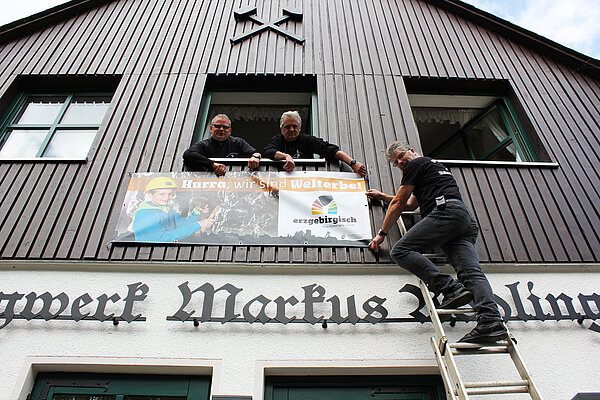 Vereinsvorsitzender Marc Schwan (rechts) bringt mit seinem Team das neue Welterbe-Banner am Besucherbergwerk Markus-Röhling-Stolln an.
Foto: Welterbe Montanregion Erzgebirge e.V.